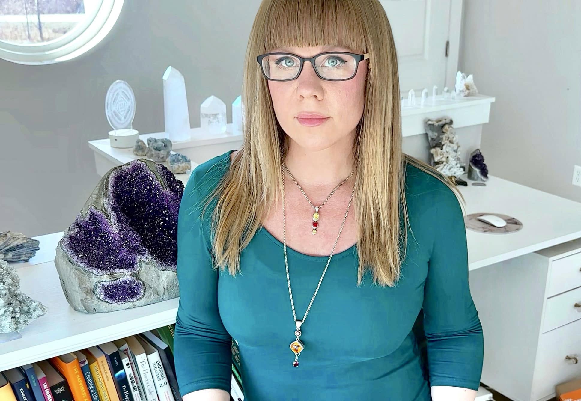 Tiffany April Raines in her gemstone workspace beside a large amethyst specimen
